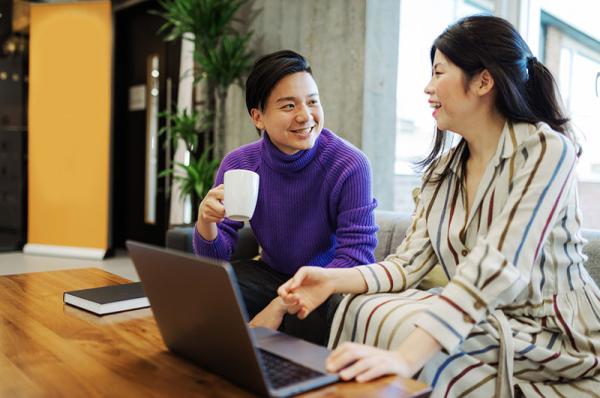 Two people chatting while using a laptop